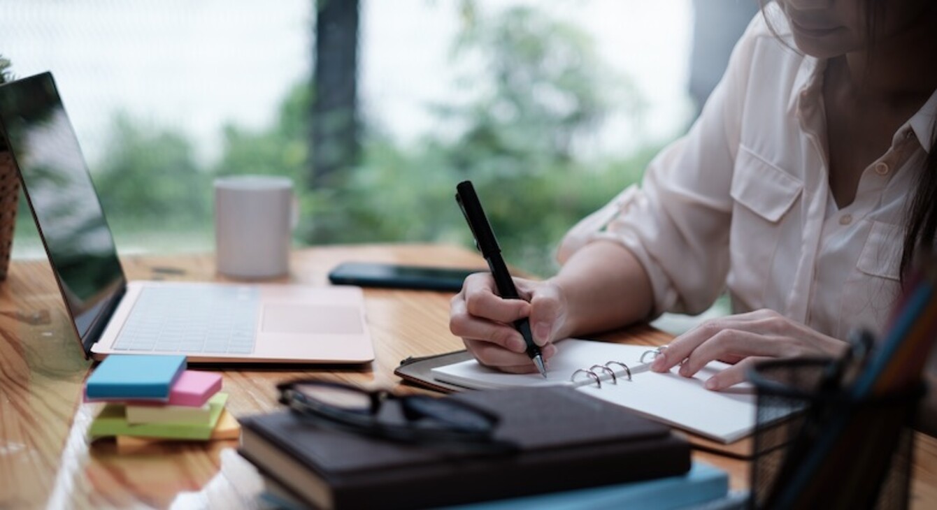 Etudiante qui travaille avec un ordinateur et qui rédige des notes