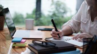 Etudiante qui travaille avec un ordinateur et qui rédige des notes