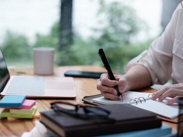 Etudiante qui travaille avec un ordinateur et qui rédige des notes